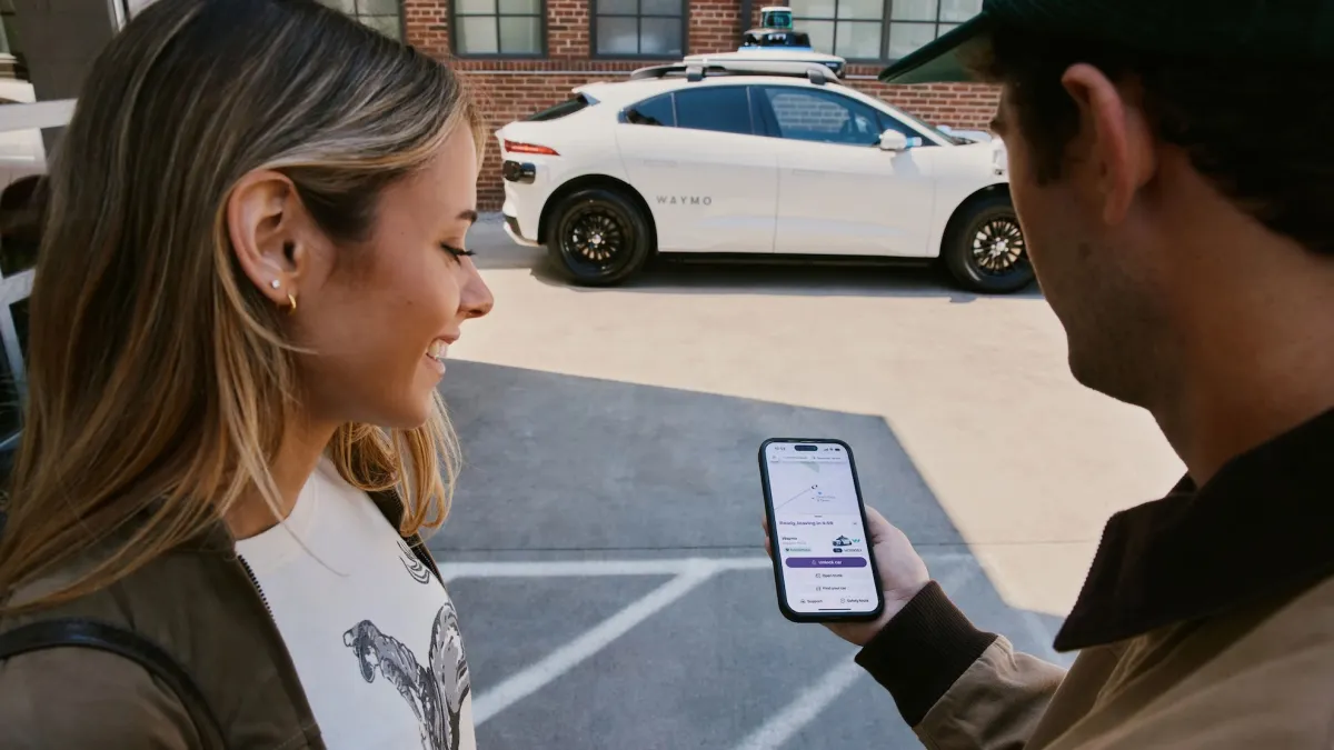 Şehir sokağında yol alan beyaz Waymo robotaksi aracı